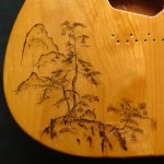 Close-up view of traditional Japanese landscape design woodburned on guitar body