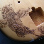 Close-up view of Koi fish design woodburned on guitar body