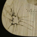 Close-up view of shattered glass design woodburned on guitar body - raw wood.